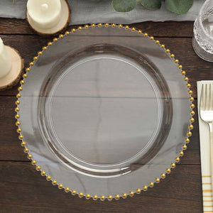 Clear glass plate with gold beaded rim on a wooden table.