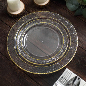 Elegant clear charger plates with textured design and gold trim on a rustic wooden table.
