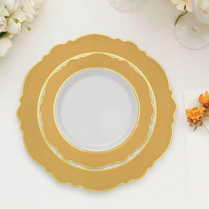 Gold decorative plates set on a table with flowers and glassware.