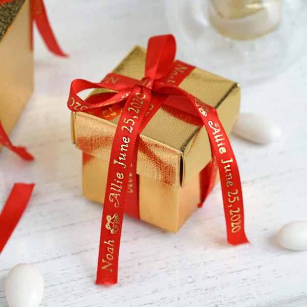 Small gold gift box with red ribbon personalized for a wedding.