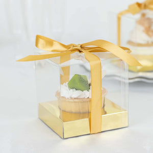 Clear dessert gift box with a golden ribbon and a cupcake inside.