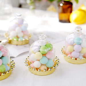 Colorful pastel candies in glass cloches with golden bases.