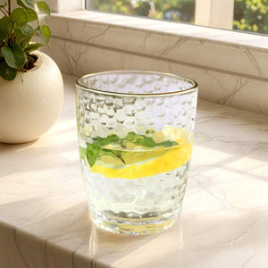 Glass tumbler with lemon and mint on a marble countertop.