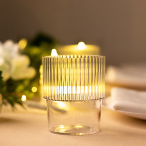 Clear ribbed glass candle holder with warm glowing light.