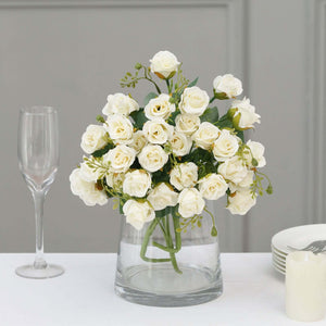 White rose bouquet in a clear vase with elegant table setting.