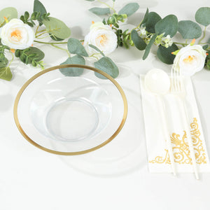 Clear glass bowl with gold rim, surrounded by floral decor and elegant utensils.