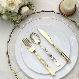 Elegant gold cutlery set on decorative white plates with floral arrangement.