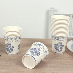 Floral design disposable cups stacked and one tipped over on a wooden table.