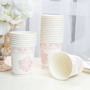 Pink floral paper cups stacked next to a vase with flowers.