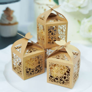 Gold decorative gift boxes with intricate designs on a white plate.