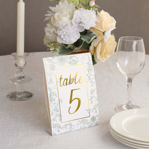 Table number card with floral design and gold accents on a dining table.