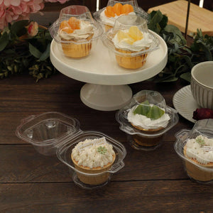Delicious assorted cupcakes in clear containers on a cake stand.