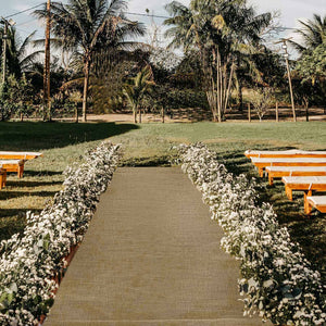 Outdoor wedding aisle with floral arrangements and wooden benches.