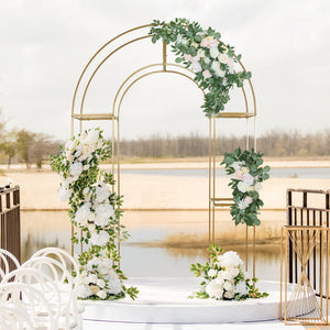 Elegant wedding arch adorned with white flowers and greenery in a scenic outdoor setting.