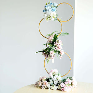 Floral display with gold rings and pastel roses on a table.