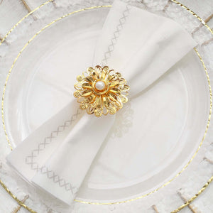 Elegant gold napkin ring with pearl on white napkin, styled on a decorative plate.