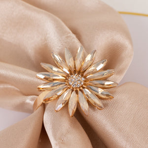 Gold flower ring with crystal accents on a satin fabric.
