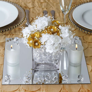 Elegant floral centerpiece with white and gold flowers, candles, and mirrored base.