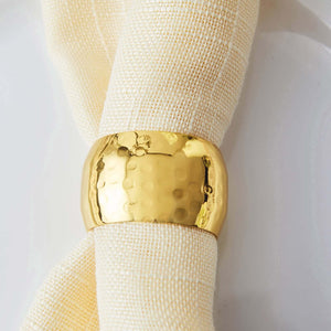Gold hammered napkin ring on a light fabric napkin.