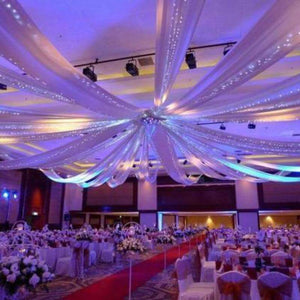 Elegant wedding reception with draped fabric and soft lighting in a grand venue.
