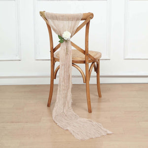 Neutral linen chair tie with white flower decoration on a wooden chair.