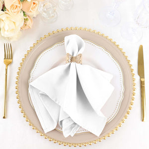 Elegant white napkin with gold ring on a decorative plate, set for dining.