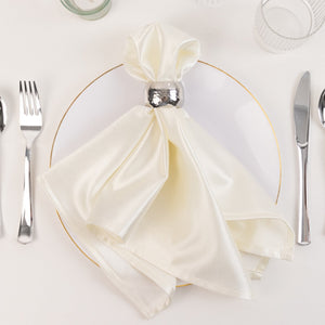 Elegant white satin napkin tied with a silver ring on a white plate.