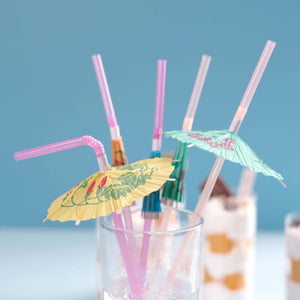 Colorful cocktail umbrellas with straws in a glass.
