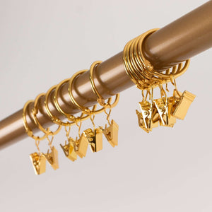 Gold curtain clip rings hanging on a rod.