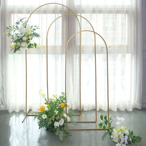Gold floral stands with greenery and flowers in a bright, airy setting.