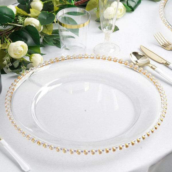 Elegant clear plate with gold beaded rim on a dining table setting.