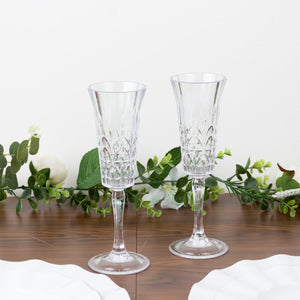 Elegant crystal champagne flutes with intricate designs on a wooden table.