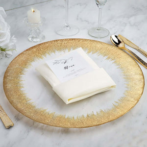 Elegant gold-rimmed plate with a folded napkin and menu card on a marble table.