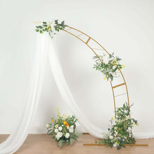 Gold arch with white drapery and floral arrangement, ideal for events or weddings.