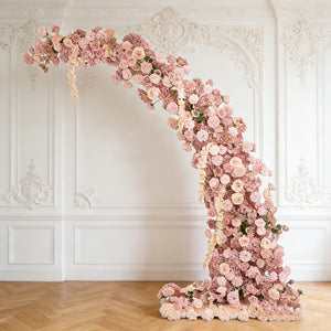 Elegant floral arch with pink roses and greenery in a stylish setting.