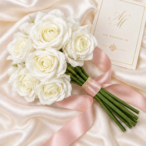White rose bridal bouquet with pink ribbon and wedding invitation card