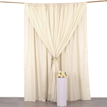 A beige solid backdrop curtain sits in front of a vase of flowers