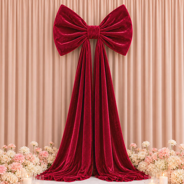 Red velvet bow and draped curtain backdrop with pastel flowers and candles