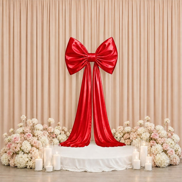 Red satin bow wedding backdrop with floral arrangements and candles
