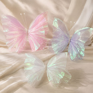 Pastel iridescent butterfly wings on soft beige fabric backdrop