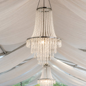 Elegant crystal chandelier hanging under a white tent ceiling