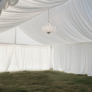 Elegant white draped tent interior with a sparkling chandelier.