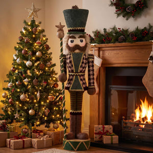 Festive Christmas nutcracker beside decorated tree and fireplace