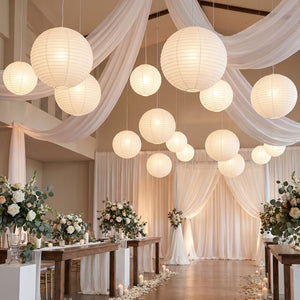 Elegant wedding reception with paper lanterns, draped fabric, and floral tablescapes