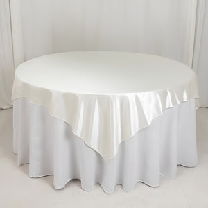 Round satin tablecloth in ivory, elegantly draped on a circular table.