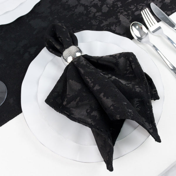 Black napkin folded on white dinner plate with silver cutlery, elegant table setting