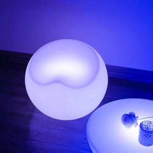 Modern round lamp with soft blue glow on wooden surface.