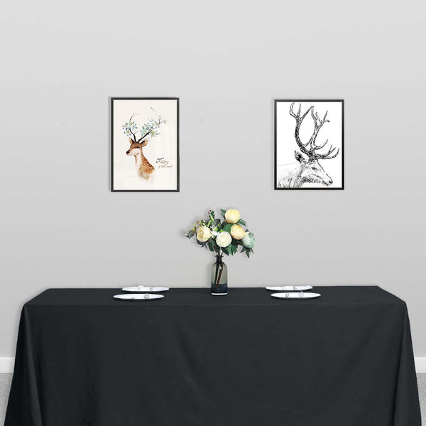 Framed deer art prints on a table with flowers in a minimalist setting.