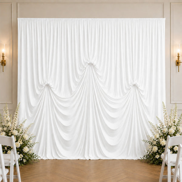 Elegant white draped wedding backdrop with floral arrangements and chairs