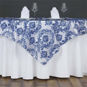 Blue and white floral tablecloth on a dining table with napkins and glasses.